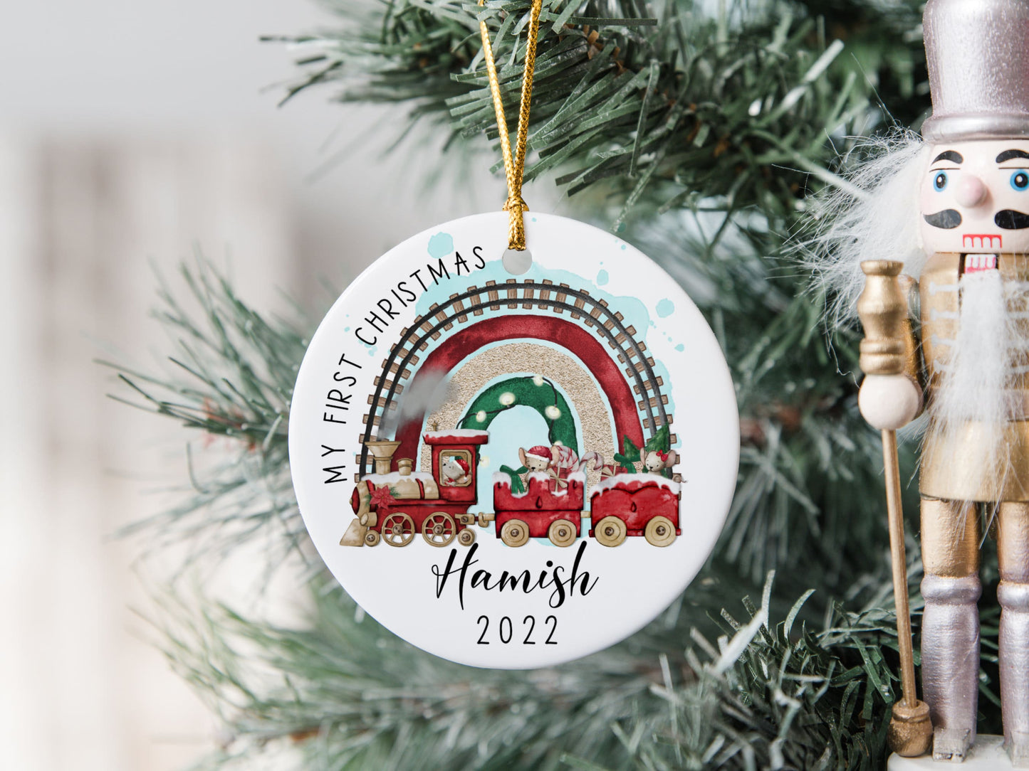 white ceramic bauble with a cute Christmas themed train and mouse design printed on with the text my first Christmas and name and year 2022 printed on