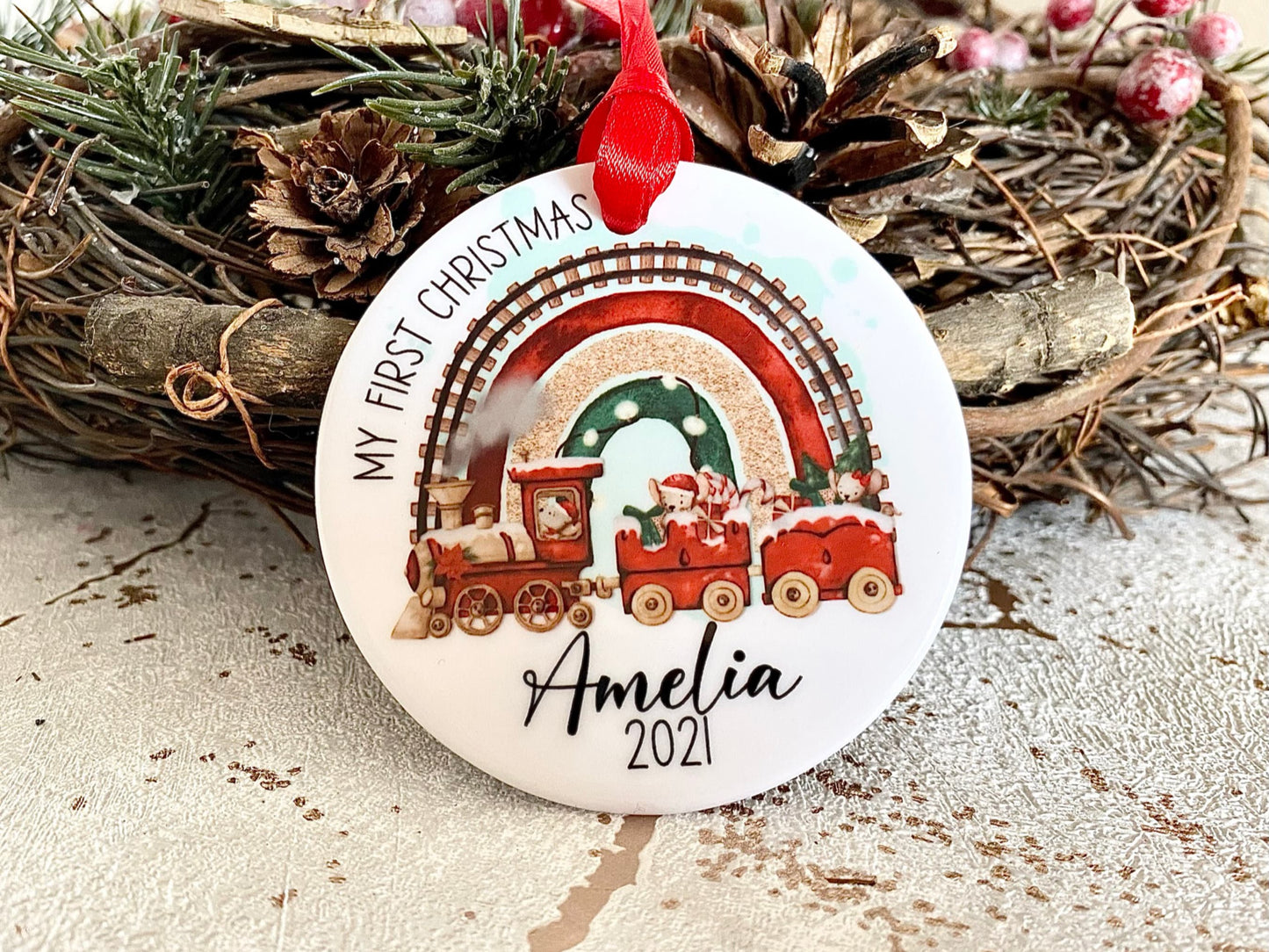 white ceramic bauble with a cute Christmas themed train and mouse design printed on with the text my first Christmas and name and year 2022 printed on