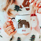woman holding a white mug with a black handle. The mug has a cute christmas pudding and mouse design printed on it with a name below
