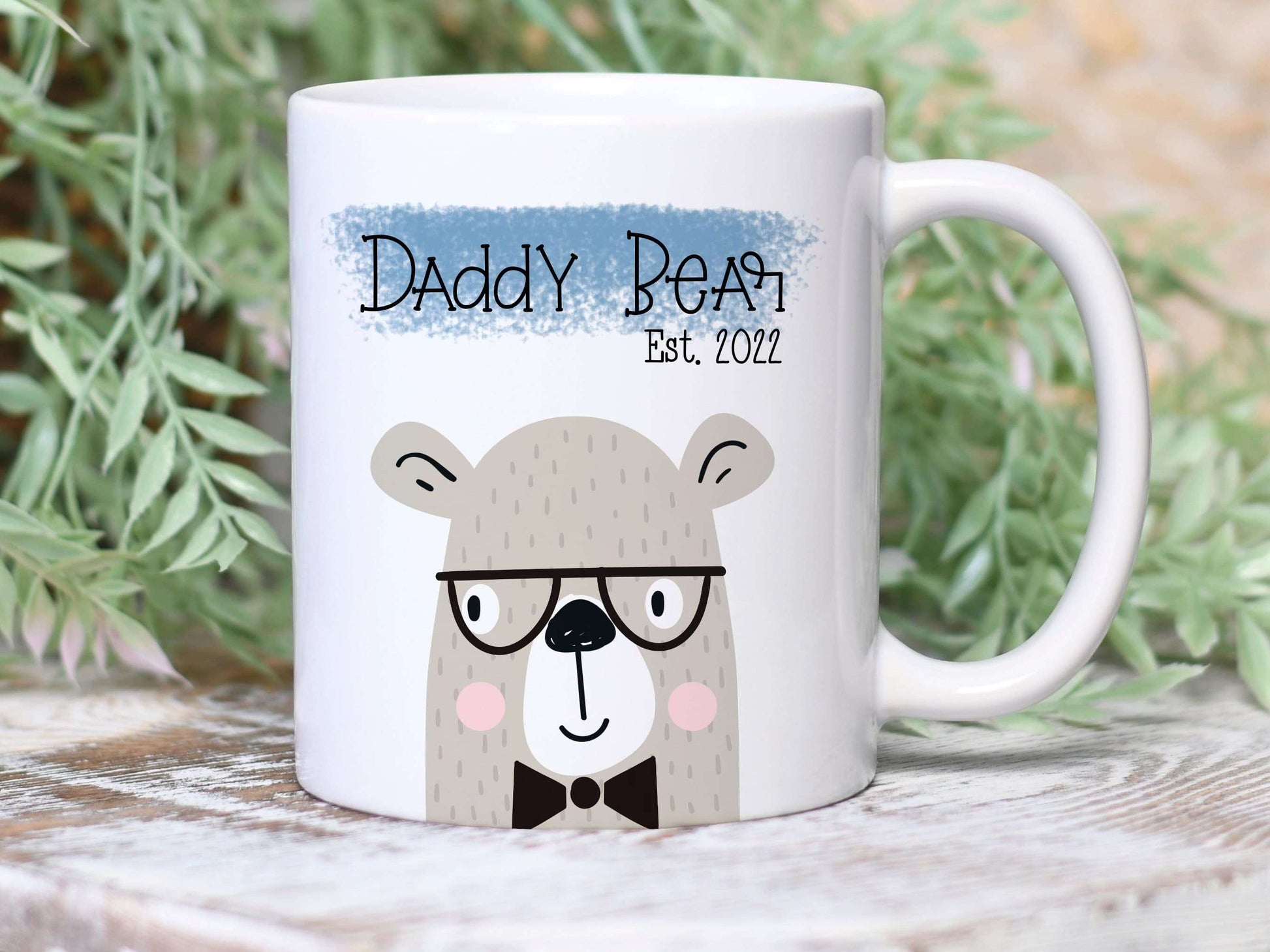 white mug with a bear illustration printed on and the text daddy bear est. 2022 printed over a blue brushdtroke above.