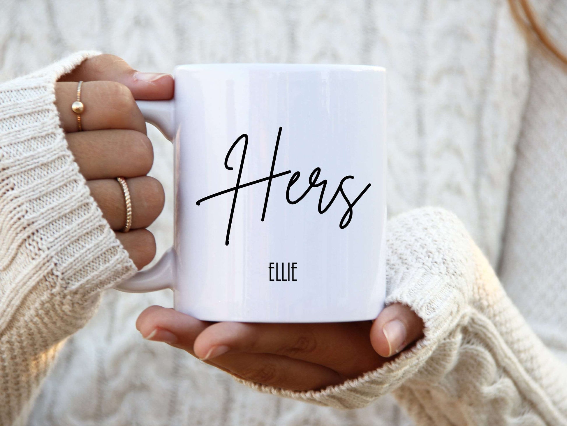 woman holding a white mug with the text Hers in a script font printed on it with a name below