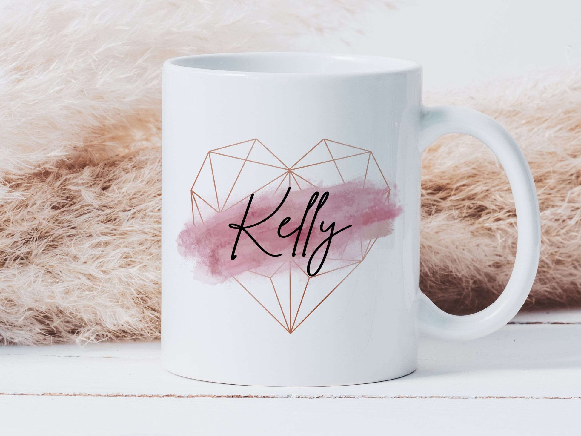 white mug with a rose gold geometric heart and pink brush stroke design with a black script name printed over the top