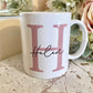white mug with a large pink H printed on with the name Helen printed over in a script font