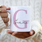 woman holding a white mug with a large pink letter G with the name Gemma printed over in a script font.