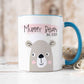 White mug with blue handle sitting on a worktop. The mug has a cute bear design printed on it with the text mummy bear above