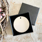black gift box with flat ceramic bauble inside