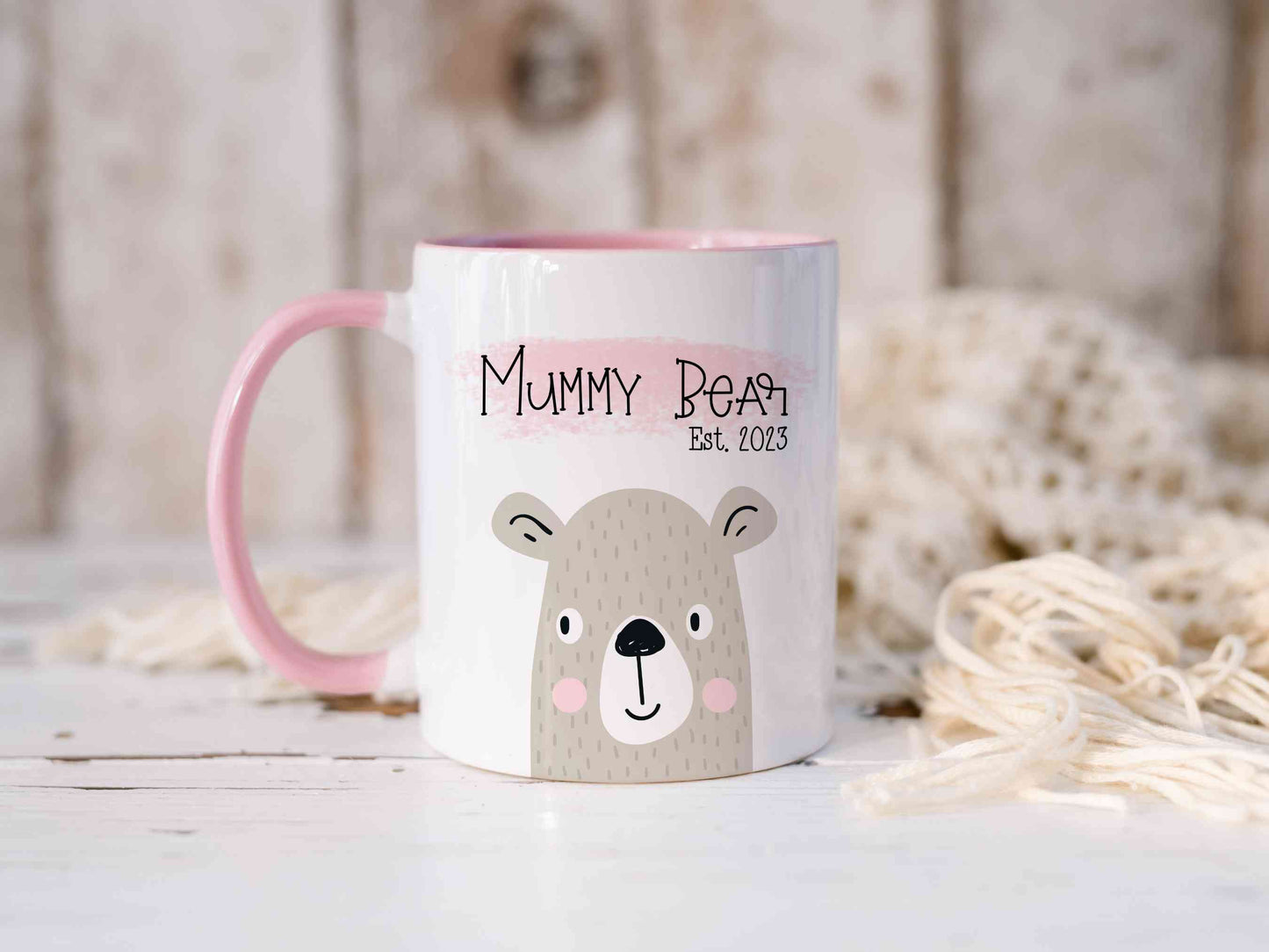 White mug with pink handle sitting on a worktop. The mug has a cute bear design printed on it with the text mummy bear above