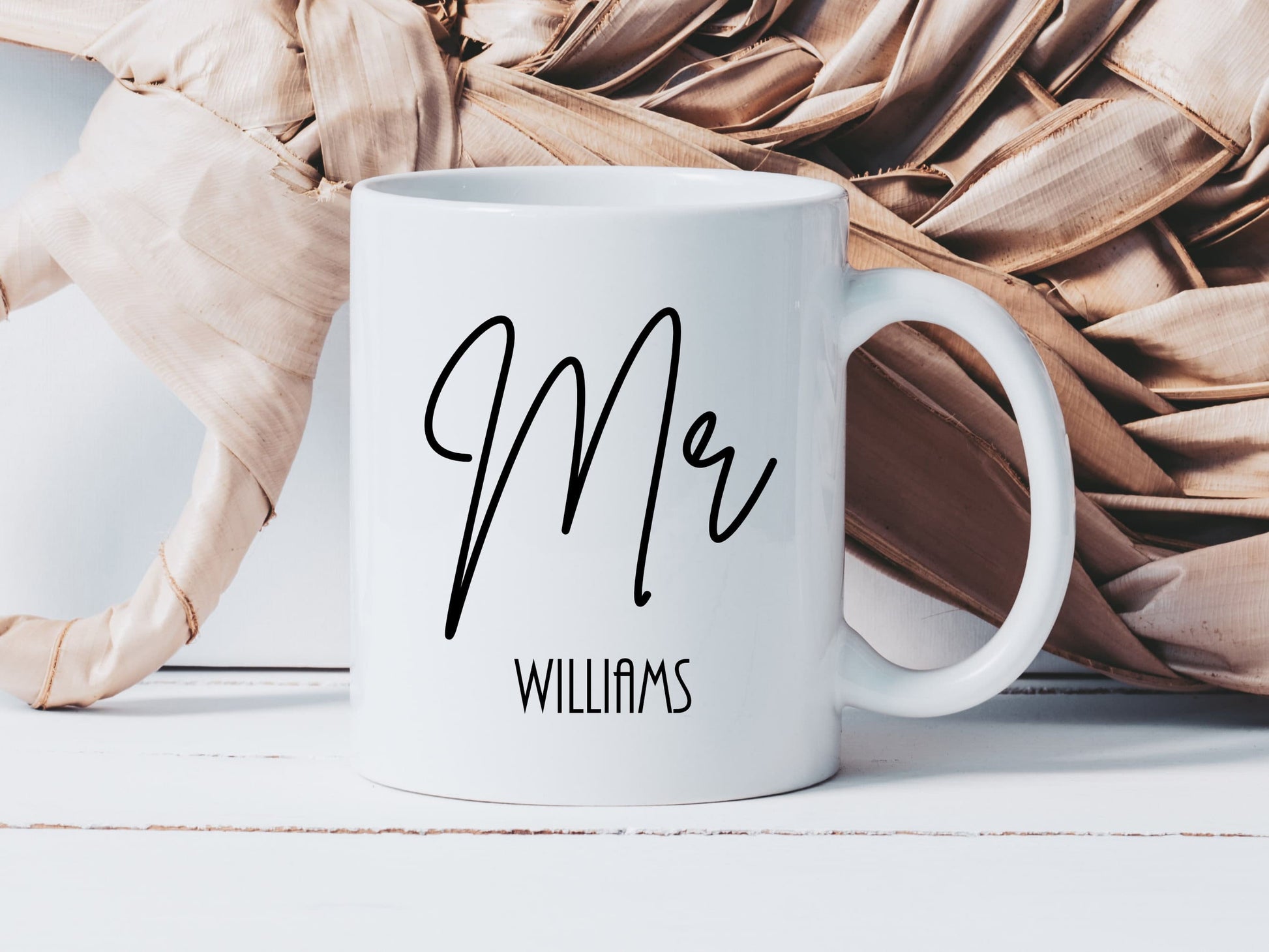 white mug with the text Mr printed in a script font. There is a surname beneath in a smaller font